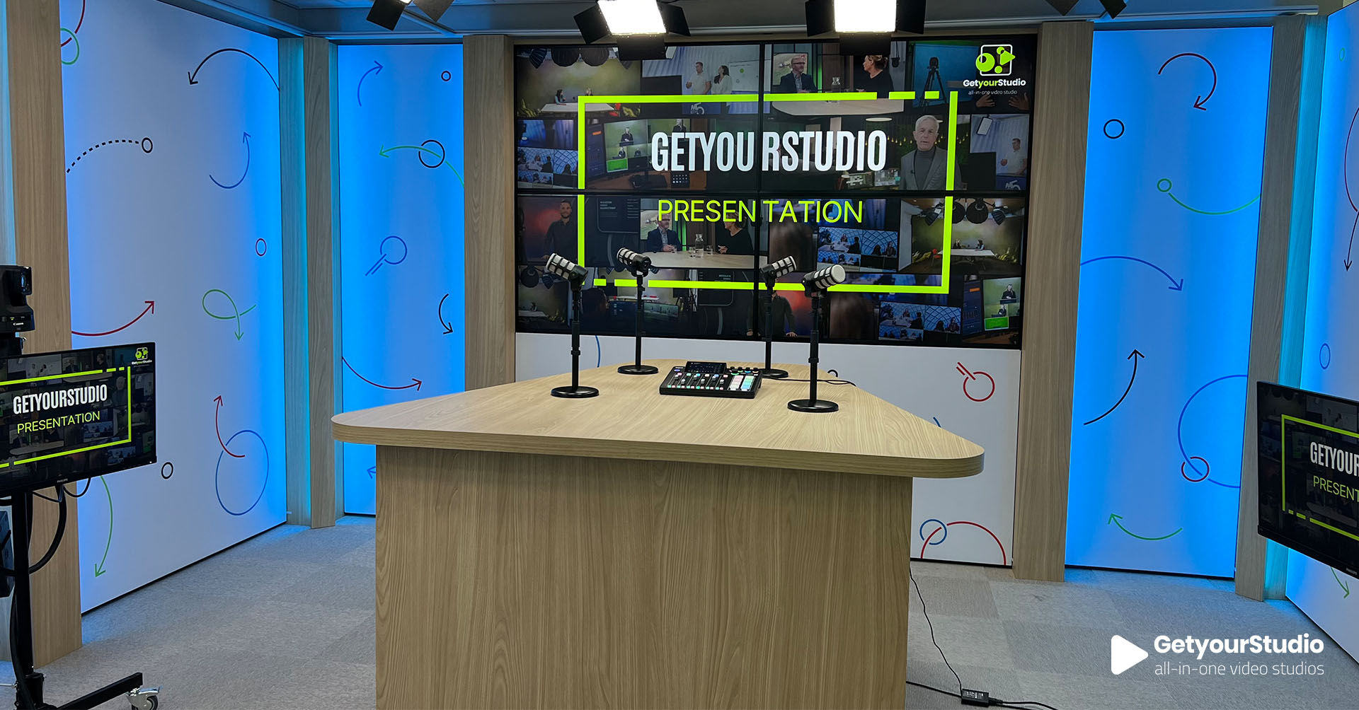 Professionele corporate videostudio met houten presentatiedesk, geïntegreerde microfoons en videowall, ontworpen door GetyourStudio